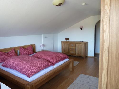 Schlafzimmer mit einem Bett mit roten Kissen und einer Kommode in der Unterkunft Ferienwohnung Hörnerblick in Fischen im Allgäu