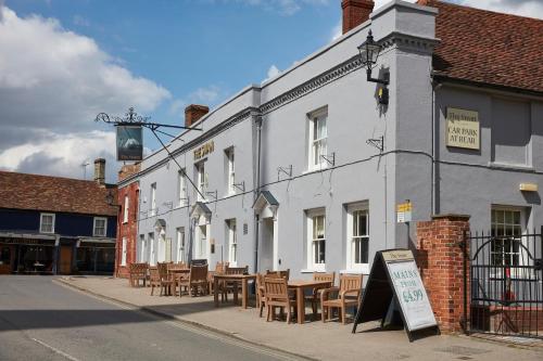 a white building with tables and chairs on a street at Swan Hotel by Greene King Inns in Thaxted