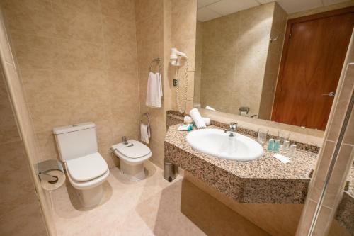 a bathroom with a sink and a toilet and a mirror at Hotel California Palace in Salou
