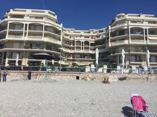 a large building on the beach in front of a building at Sharon Apartment in Victoria Beach in Menton