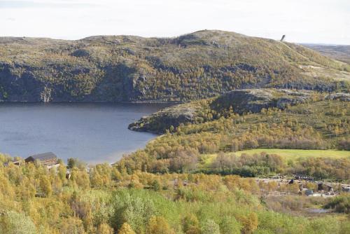 a lake in the middle of a mountain with trees at Snowhotel Kirkenes in Kirkenes