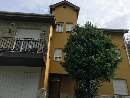 a yellow building with a tree in front of it at Os Arroxos in Trabadelo