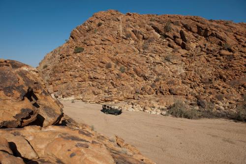 a jeep parked in front of a rocky mountain at Tutwa Desert Lodge in Augrabies