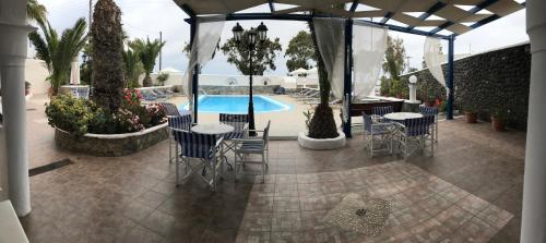 a patio with tables and chairs and a swimming pool at Villa Ilios in Fira