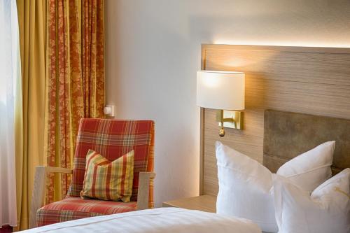 a bedroom with a bed and a chair and a lamp at Hotel Thomahof in Hinterzarten