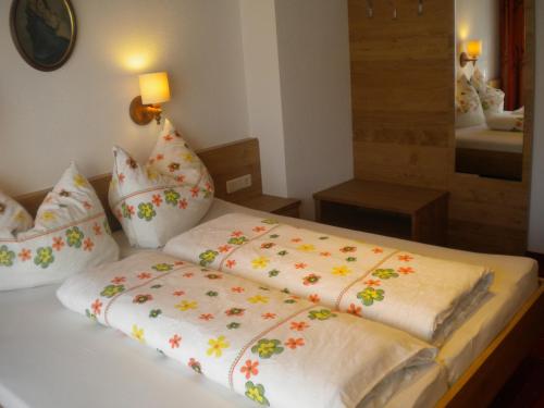 ein Bett mit einer weißen Bettdecke mit Blumen darauf in der Unterkunft Erika Sporer in Hippach