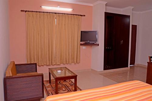 a bedroom with a bed and a tv and a table at Hotel Shikhar & Restaurant in Almora