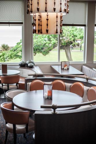 a dining room with tables and chairs and windows at Seamill Hydro Hotel in Seamill