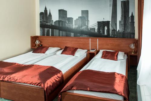 two beds in a hotel room with a picture of a city at Europa Hotel És Étterem in Nyíregyháza