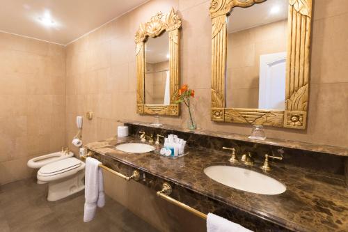 a bathroom with two sinks and a toilet and mirrors at Claridge Hotel in Buenos Aires