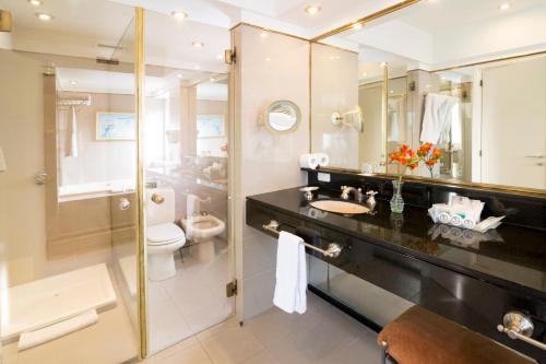 a bathroom with a sink and a toilet and a mirror at Claridge Hotel in Buenos Aires