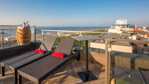 a balcony with a table and chairs on top of a building at Michels Strandhotel Germania in Norderney