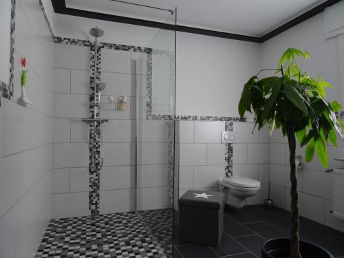 baño con ducha, aseo y planta en Haus Am Sonnenberg, en Ulmen