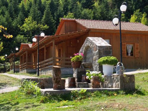 a wooden cabin with flowers in front of it at Livadaki Village in Megáli Kápsi