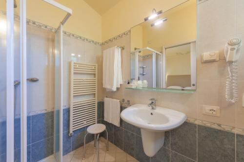 La salle de bains est pourvue d'un lavabo et d'une douche. dans l'établissement Hotel Saturno Fonte Pura, à Saturnia
