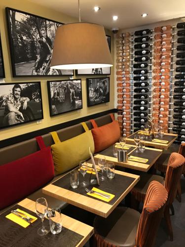 a restaurant with tables and chairs and wine racks at Hotel l'Avenue in Chantilly