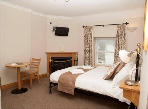 a bedroom with a bed and a table and a window at The Spread Eagle Hotel in Jedburgh