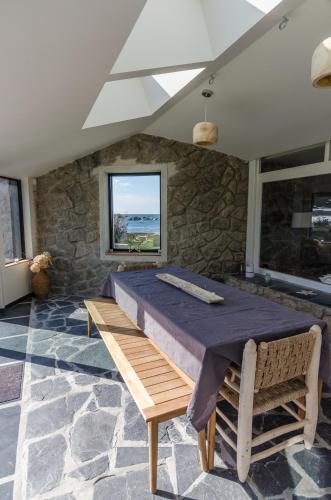 Cette chambre est dotée de murs en pierre, d'une table et d'une fenêtre. dans l'établissement Maison de La pointe, à Brignogan-Plage