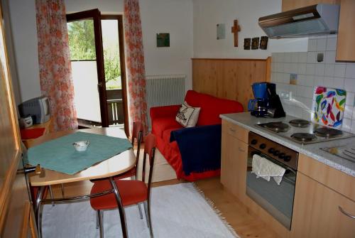 uma cozinha com uma mesa e uma pequena cozinha com um sofá vermelho em Treindlhof em Fuschl am See