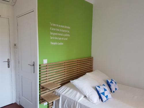 a bedroom with a bed with a green wall at Villa TerraMera Hôtel in Le Lavandou