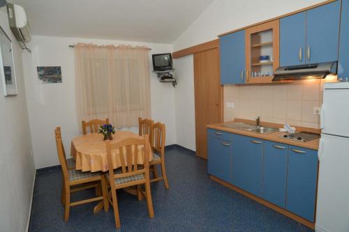cocina con mesa y cocina con armarios azules en Apartments Lonić, en Kukljica