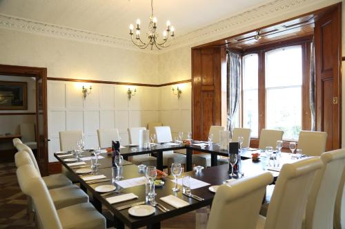 una sala de conferencias con una mesa larga y sillas blancas en Keswick Park Hotel, en Keswick