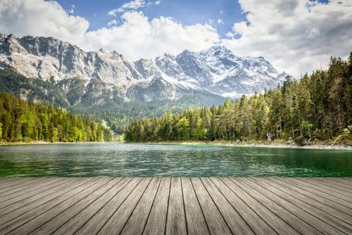 a wooden boardwalk next to a lake with mountains at Luftikus Lodge in Garmisch-Partenkirchen