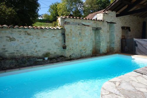 une piscine bleue à côté d'un mur en pierre dans l'établissement Mas de la Combe Cachée, à Villefranche-de-Rouergue