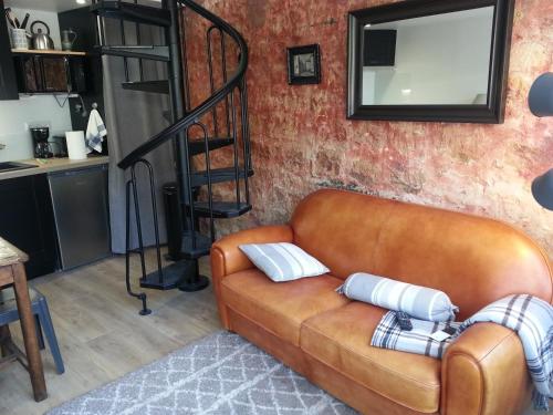 um sofá de couro castanho numa sala de estar com um espelho em GÎTE DU VALAMBOURG em Auvers-sur-Oise