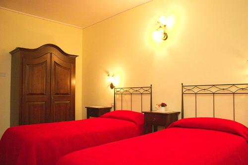 1 dormitorio con 2 camas rojas y puerta en Agriturismo Le Gazze, en Camposanto