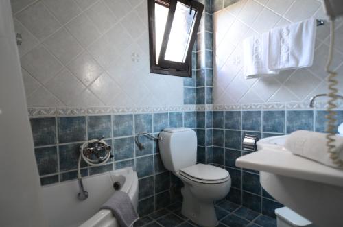 a blue tiled bathroom with a toilet and a sink at Penelope Apartment Hotel in Dassia