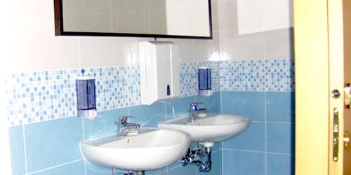 a bathroom with two sinks in a blue tiled wall at Hotel Moja in Cesenatico