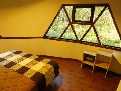 a bedroom with a bed and a large window at Cuyinco Domos in Riñinahue
