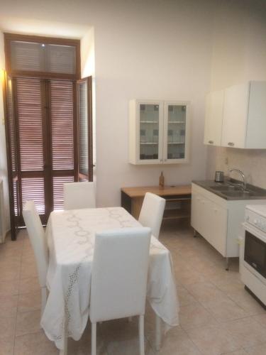 チビタベッキアにあるWHOLE HOLIDAY HOME APARTMENT FANTASTIC CIVITAVECCHIA da Pamino & Priscilla con due Camere letto!の白いテーブルと白い椅子、テーブルとカウンターのあるキッチン