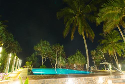 a swimming pool at night with palm trees at Czech House in Tangalle