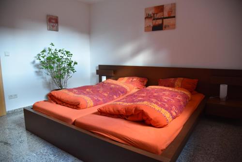 ein Bett mit orangefarbener Bettwäsche und Kissen darauf in der Unterkunft Ferienwohnung Inzlingen in Inzlingen