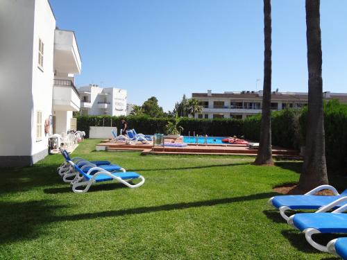 a lawn with lounge chairs and a swimming pool at Venecia Apartments in Port d'Alcudia