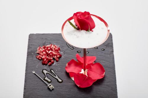 a cocktail with red flowers on a black table with scissors at Absolute Mykonos Suites & More in Mikonos