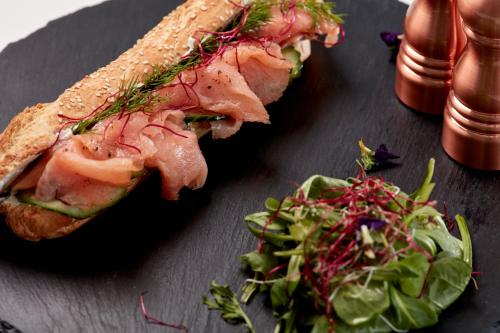 a sandwich and a salad on a black plate at Absolute Mykonos Suites & More in Mikonos