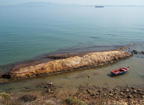 a small boat sitting on the shore of a body of water at Aeriko Benovias Rooms & Apartments in Karfas