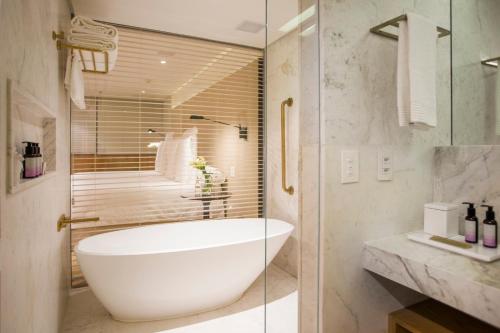 a bathroom with a white tub and a shower at Emiliano Rio in Rio de Janeiro