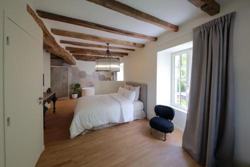 a bedroom with a bed and a chair and a window at Le Moulin De Nanteuil in Migné-Auxances