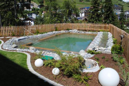 einen Pool in einem Garten mit einem Holzzaun in der Unterkunft Apart Sonnenplateau in Serfaus