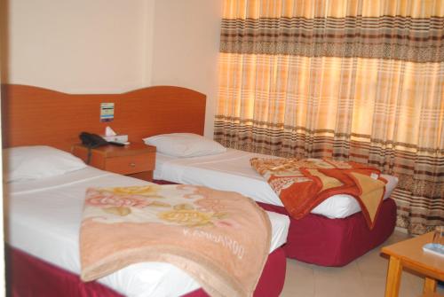 a hotel room with two beds and a window at Praasad Paradise in Cox's Bazar