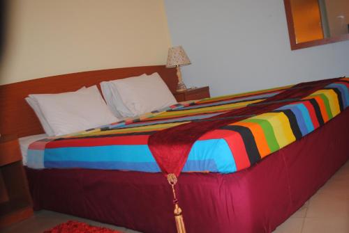 a bed with a colorful blanket on top of it at Praasad Paradise in Cox's Bazar