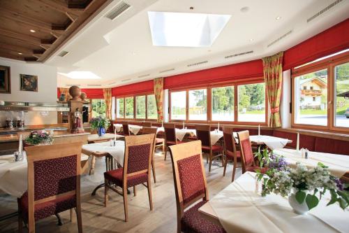 um restaurante com mesas, cadeiras e janelas em Gasthof Skirast em Kirchberg in Tirol