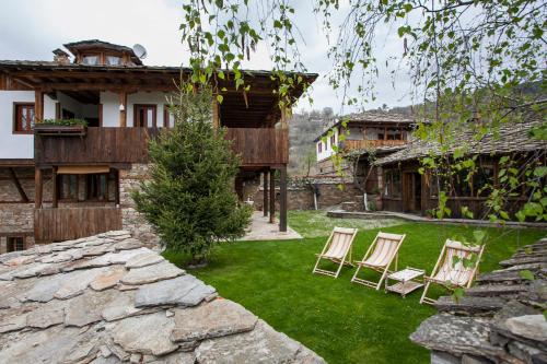 un patio con 2 sillas y una pared de piedra en Lavanda Restaurant with Rooms en Kovachevitsa