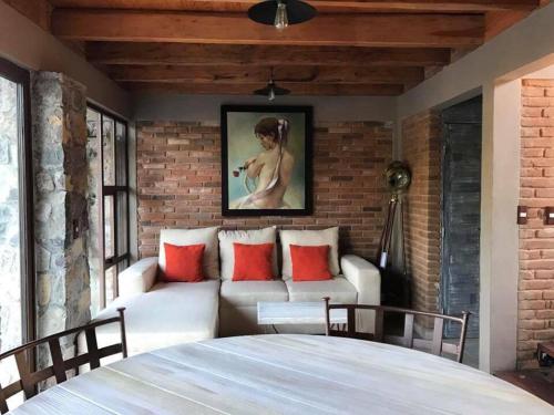 a living room with a white couch and a brick wall at Casa Ndomi in Valle de Bravo