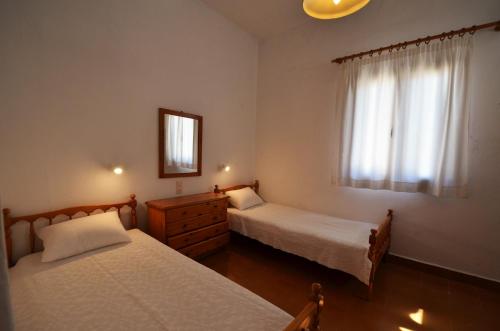een slaapkamer met 2 bedden en een raam bij Madoupa Beach Apartments in Ornos