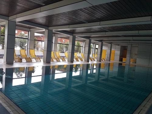 a swimming pool with yellow chairs in a building at Ferienwohnung Pichlarn in Aigen im Ennstal